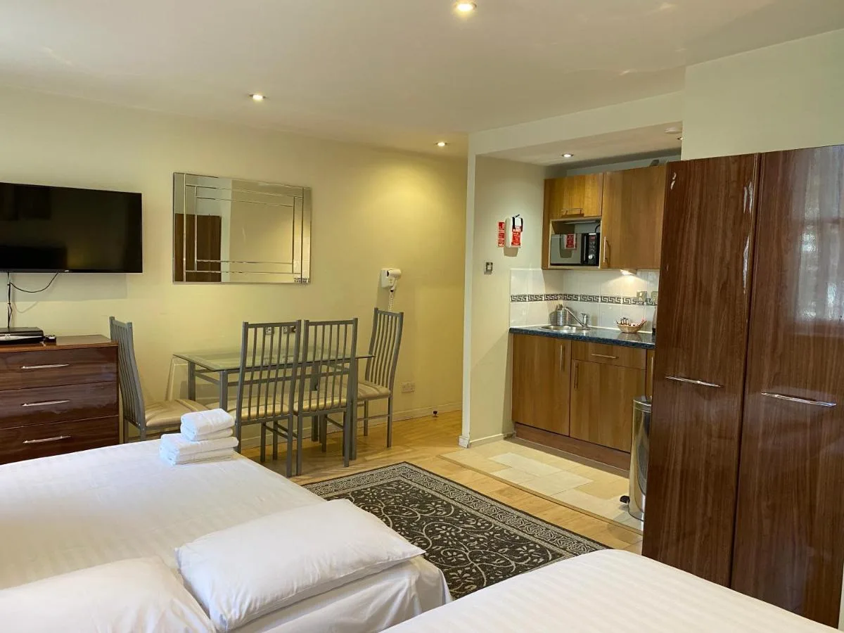 a bedroom with two beds and a kitchen with a table at Grand Plaza Serviced Apartments in London